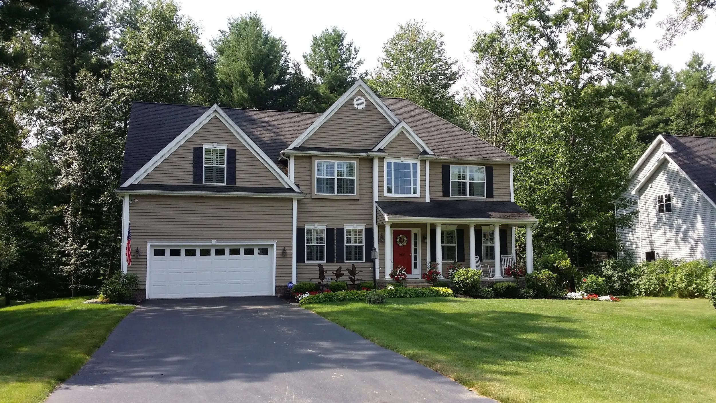 Tan two-story Colonial with black shutters and a red front door