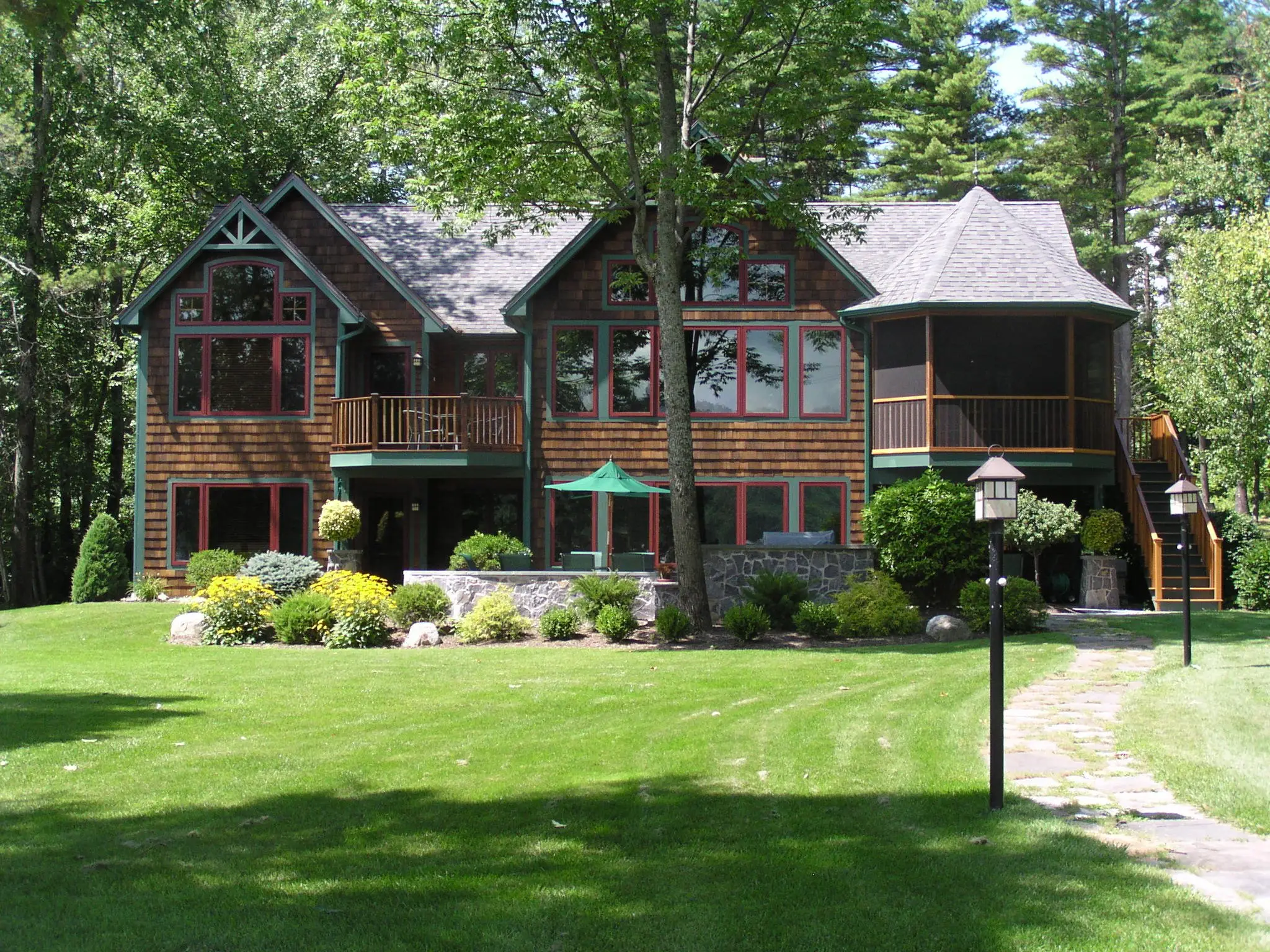 Cedar-shingled lake home with a screened gazebo porch and a wide lawn