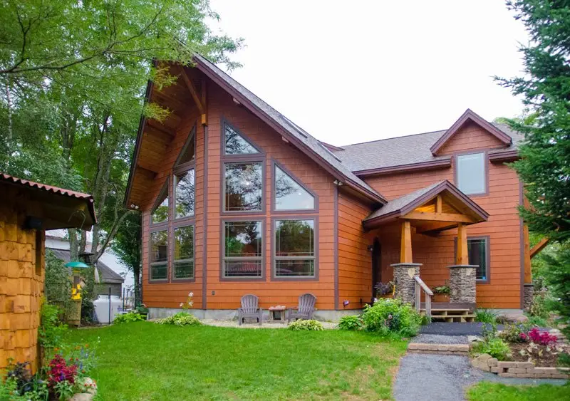 Cedar home with a tall gable of windows and a timber-framed entry