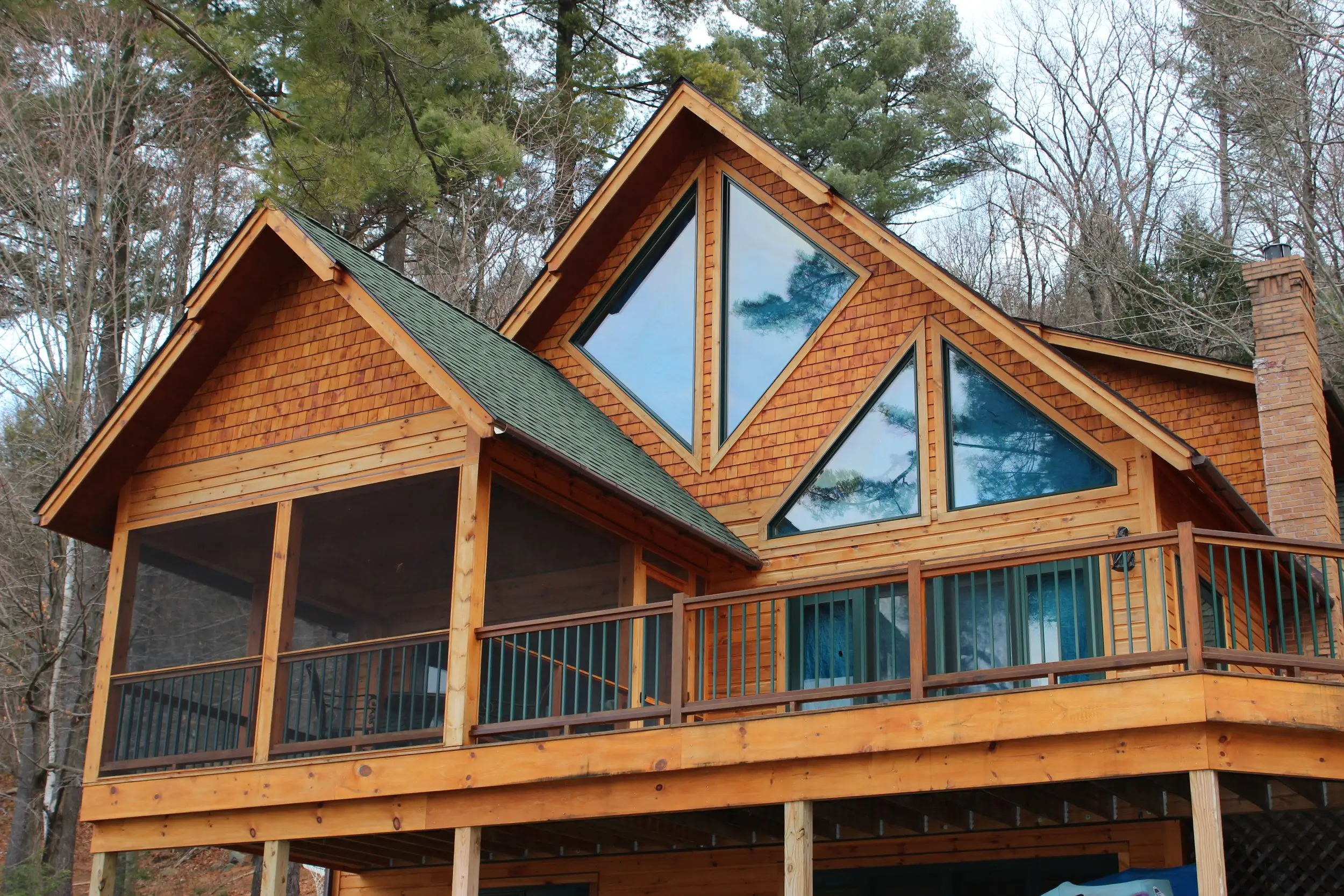 Cedar home with tall triangular windows and a screened porch