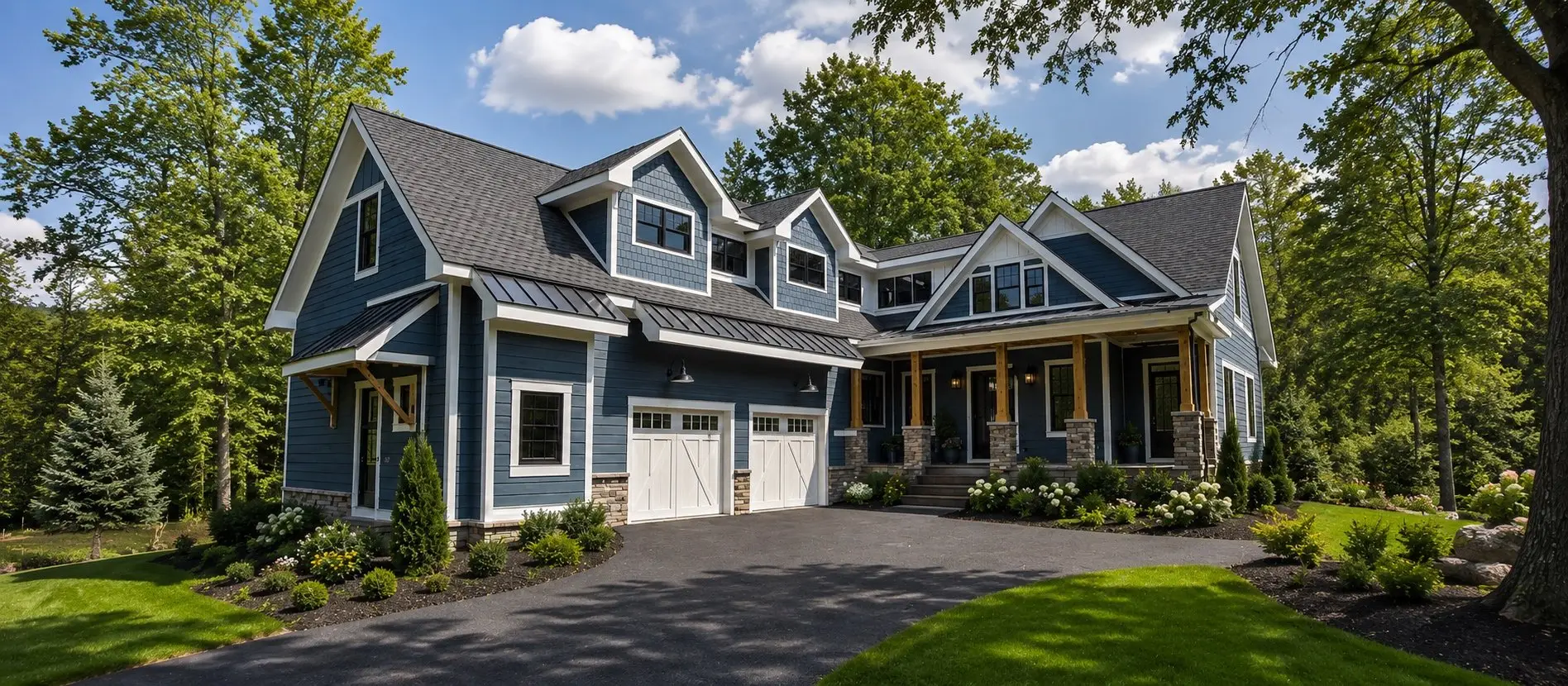 Blue-gray two-story home with white trim, a stone-columned front porch and a two-car garage